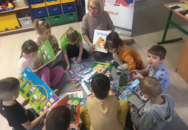 Pani bibliotekarka z przedszkolakami oglądającymi książki